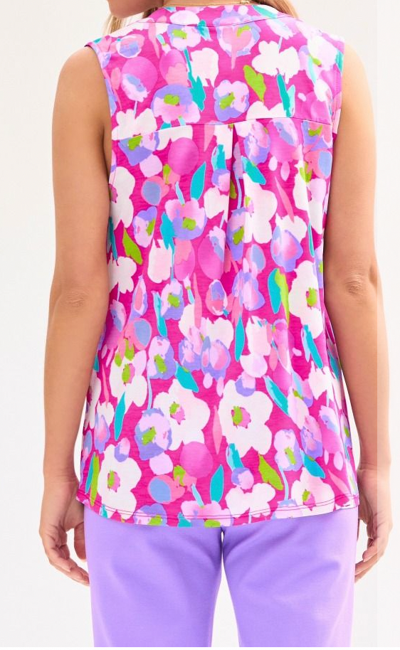 Person wearing a sleeveless floral top with a pink background