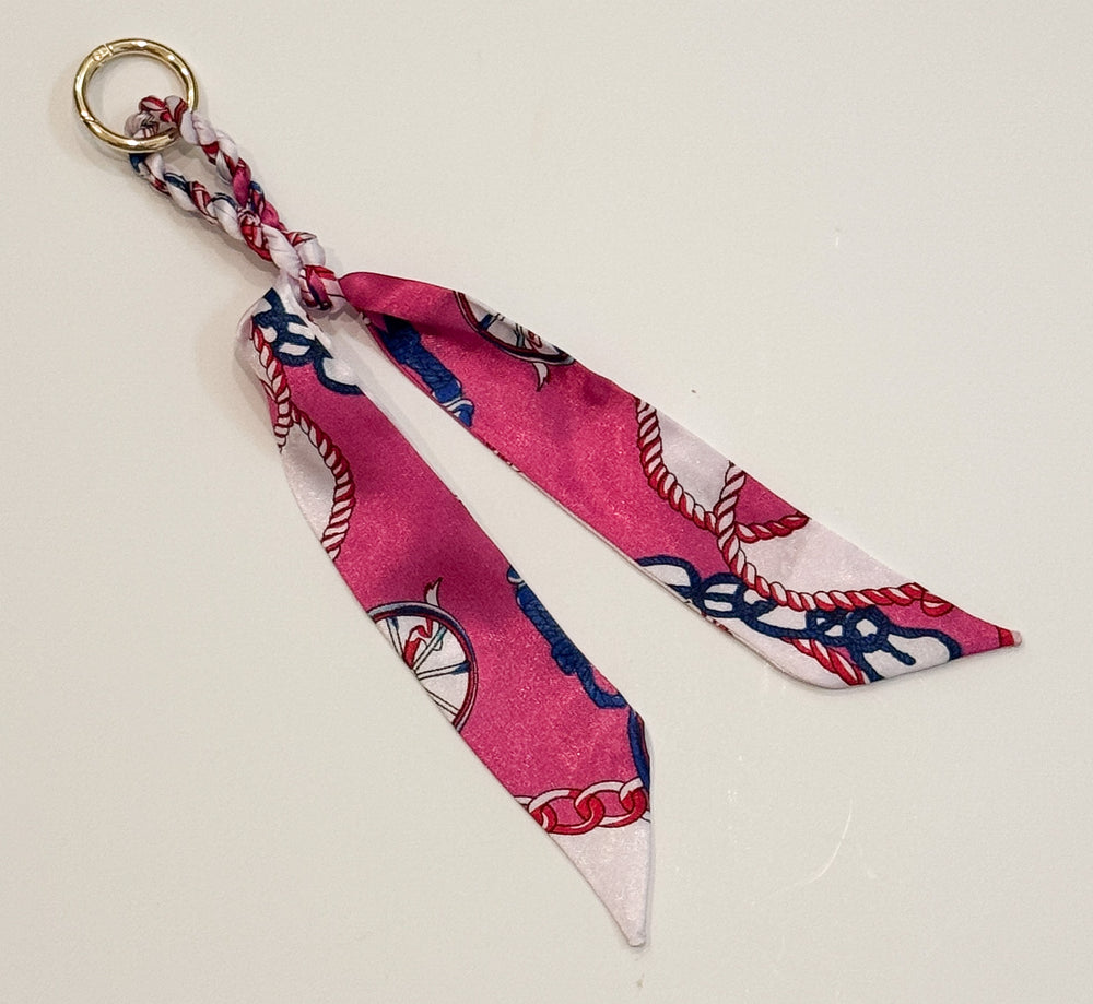 Fabric purse charm with pink and white pattern on a light gray background