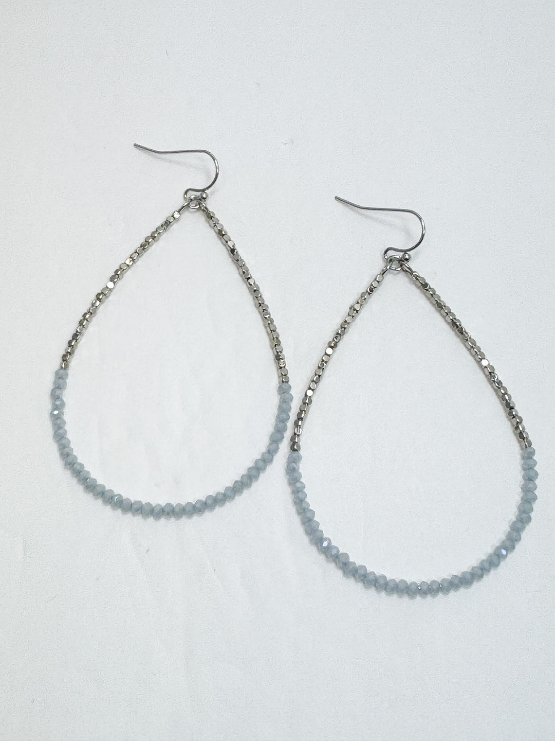 Teardrop-shaped beaded earrings on a light gray background