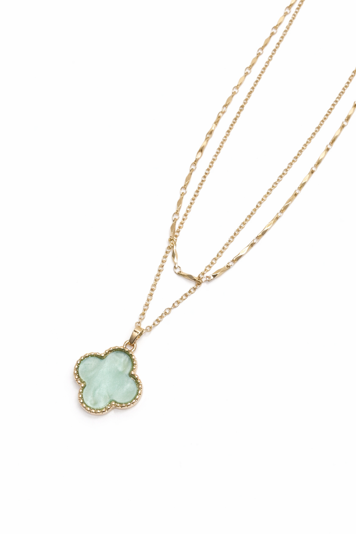 Gold necklace with a clover-shaped pendant on a white background