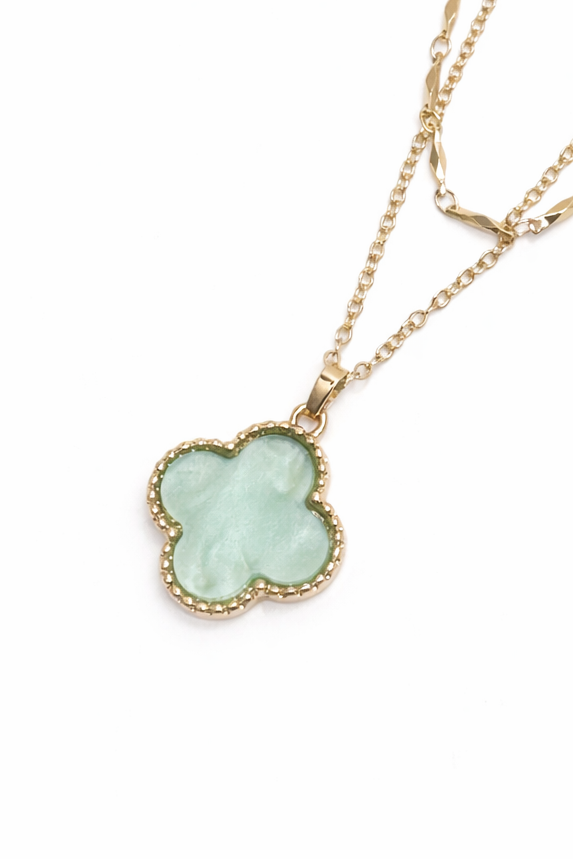 Gold necklace with a clover-shaped pendant on a white background