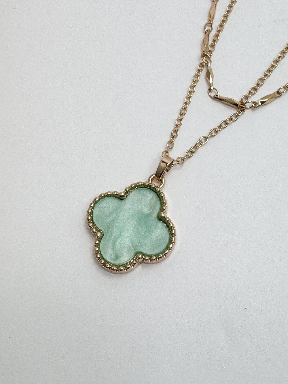 Necklace with a green clover-shaped pendant on a white background