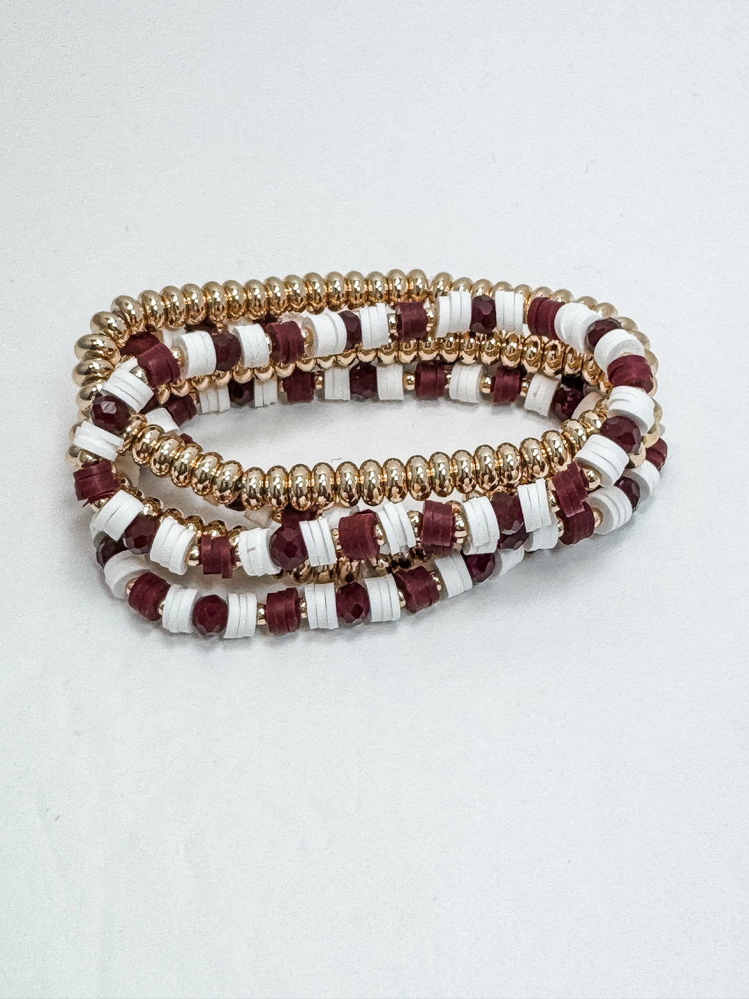 Set of beaded bracelets with gold, red, and white pattern on a light gray background