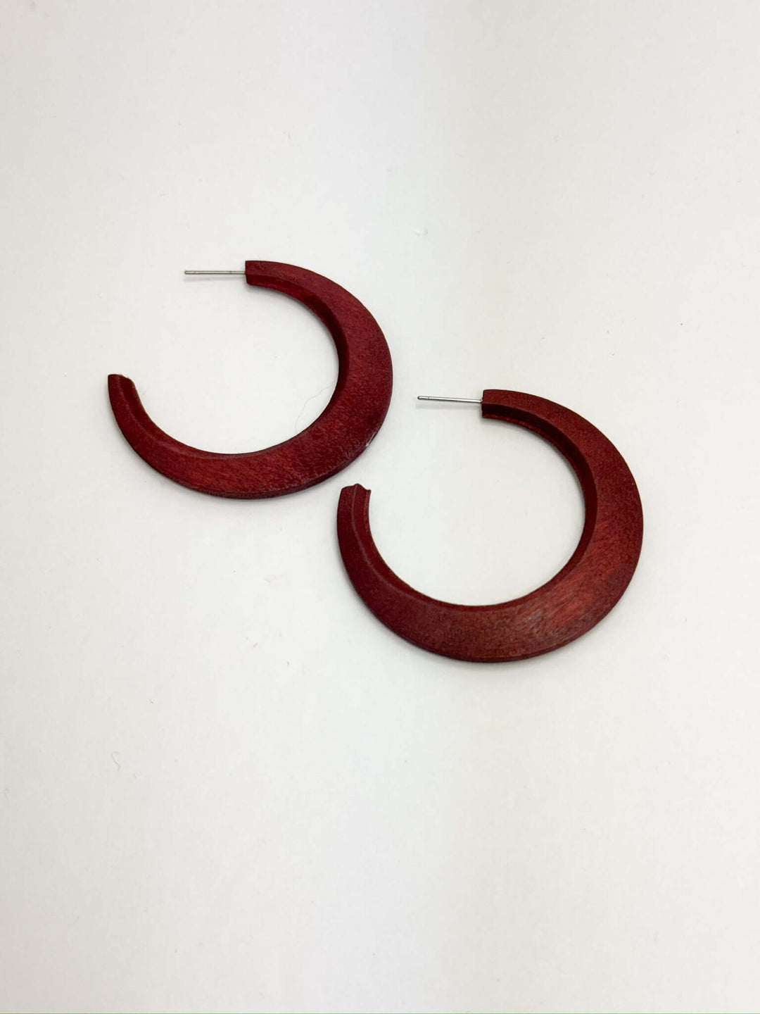 A pair of maroon wooden hoop earrings with lightweight design, displayed against a white background.
