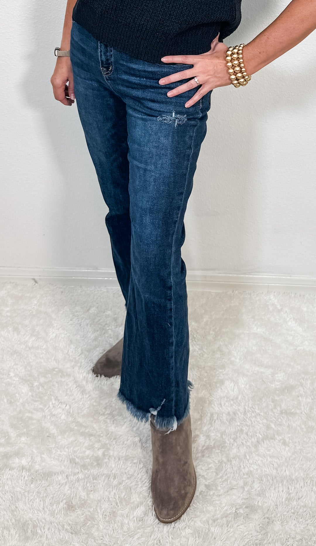 Person wearing blue jeans and brown boots on a light gray background