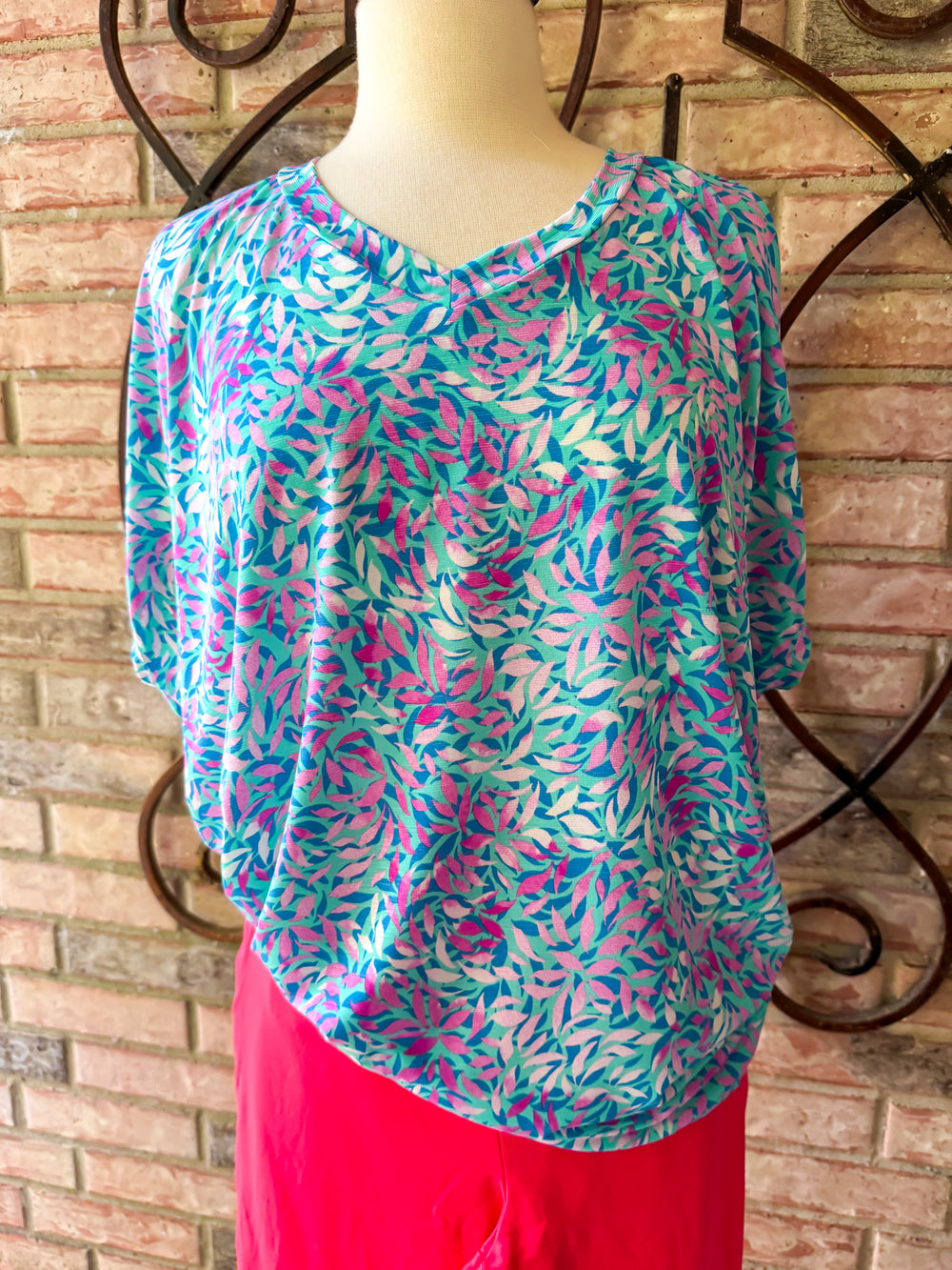Colorful patterned top on a mannequin against a brick wall