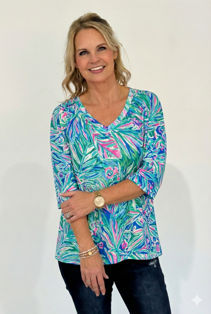 Woman wearing a colorful patterned top with a plain background