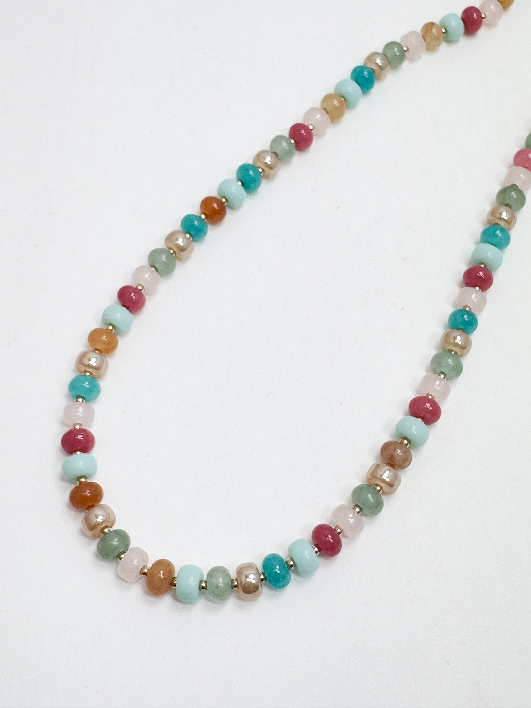 A multicolored beaded necklace with a blend of coastal blue, blush pink, amber, and terracotta colors.