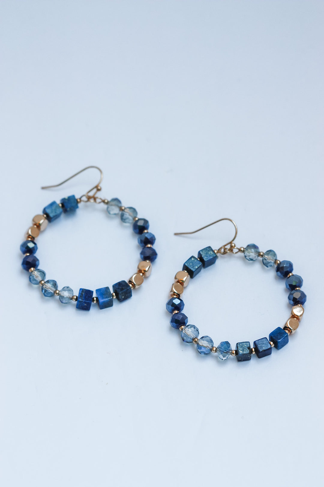 Pair of beaded hoop earrings on a light blue background