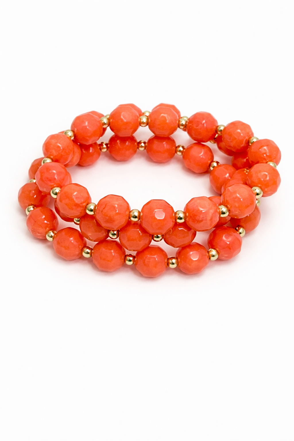 Stack of orange beaded bracelets with gold accents on a white background