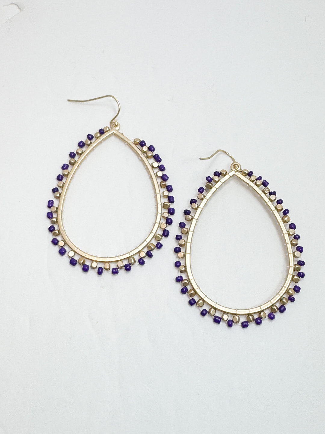 Teardrop-shaped earrings with purple beads on a white background