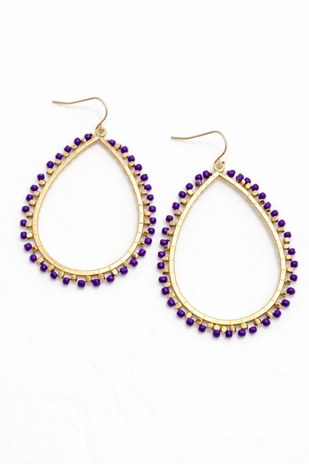 Gold hoop earrings with purple beads on a white background