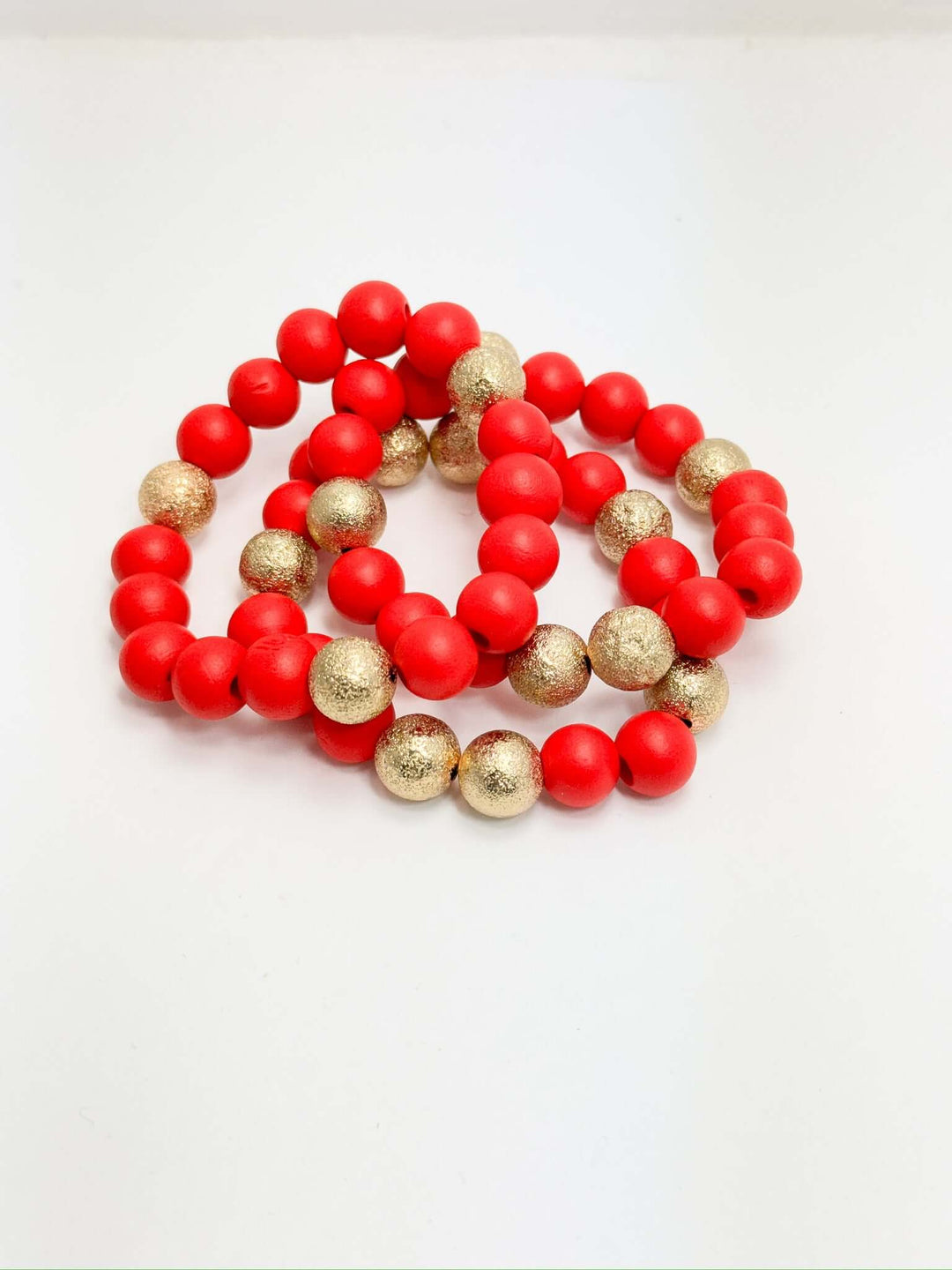 A set of three red bracelets with gold accents on a white background.