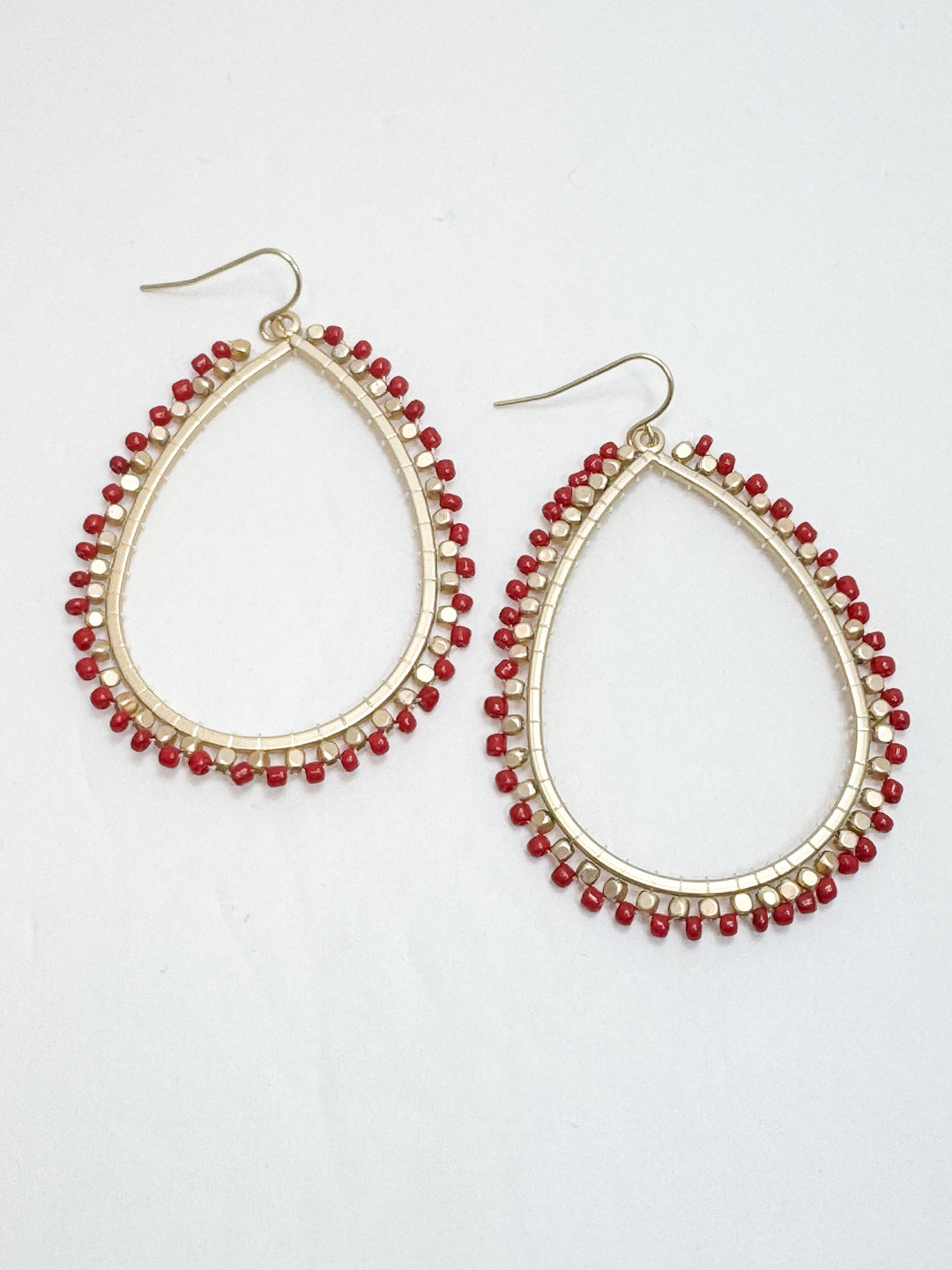 Teardrop-shaped earrings with red beads on a white background