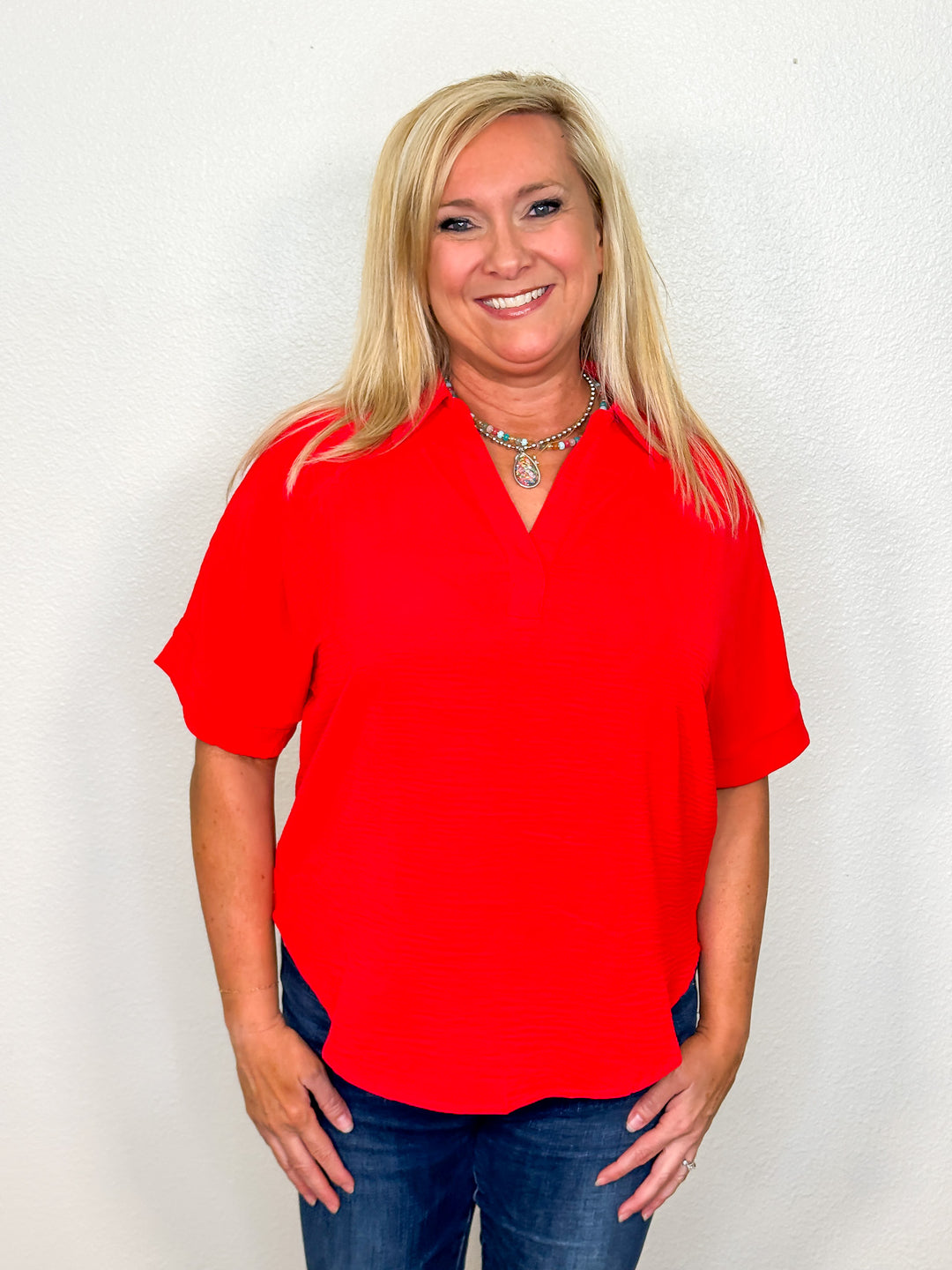 Woman wearing a red blouse and blue jeans against a white background