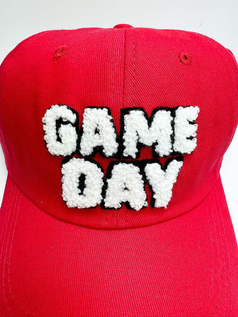 A red baseball cap with 'Game Day' text embroidered in white on the front.