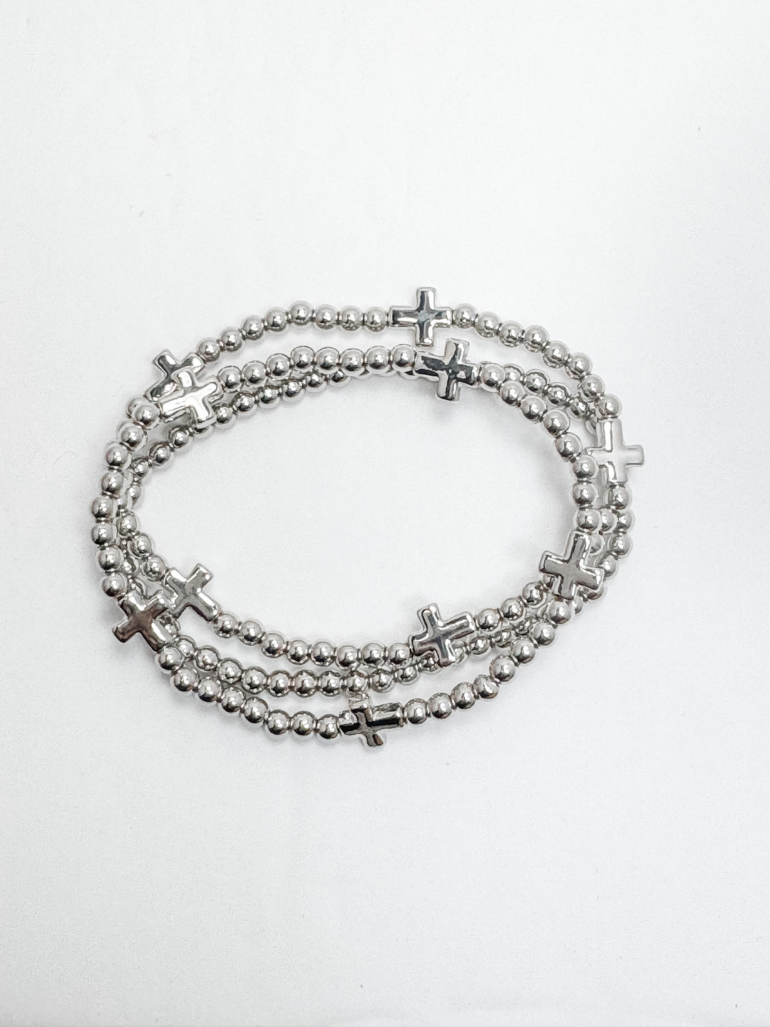 A set of two stackable silver bracelets with cross accents on a white background.