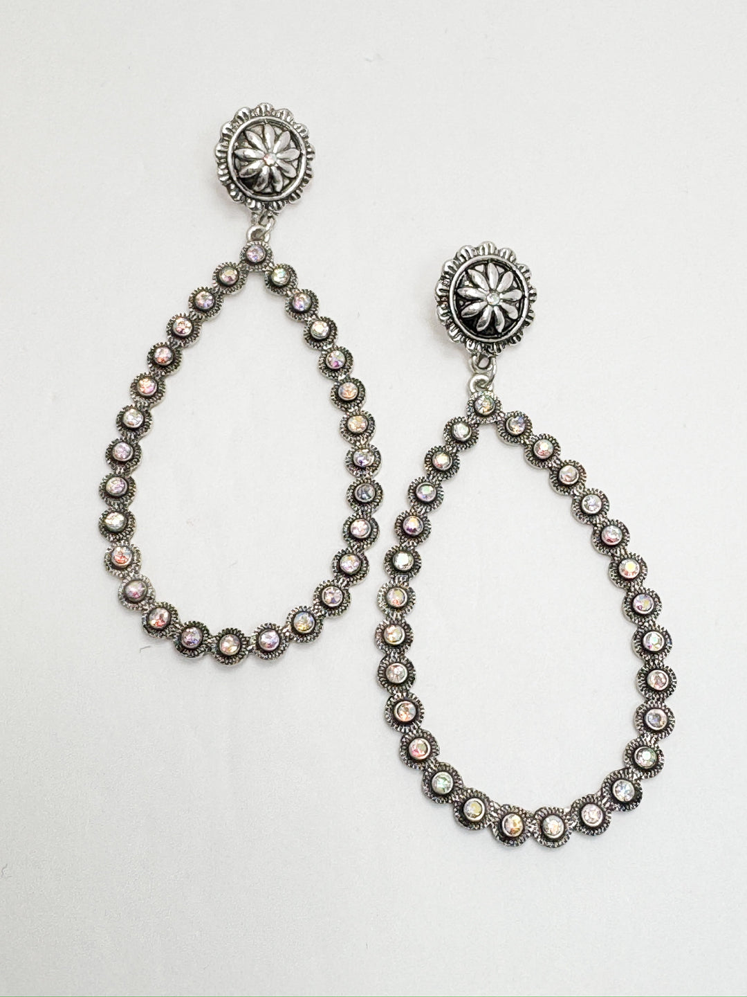 A pair of dangling earrings with concho post studs and teardrop-shaped drops covered in rhinestones.