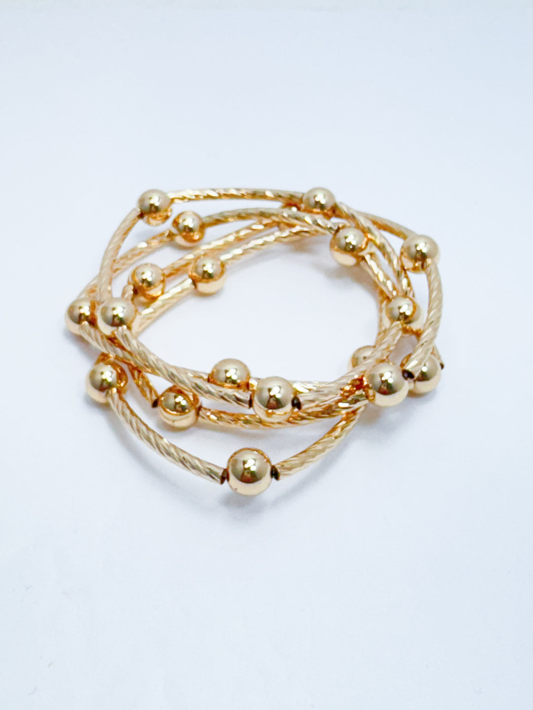 Gold beaded bracelet on a light gray background