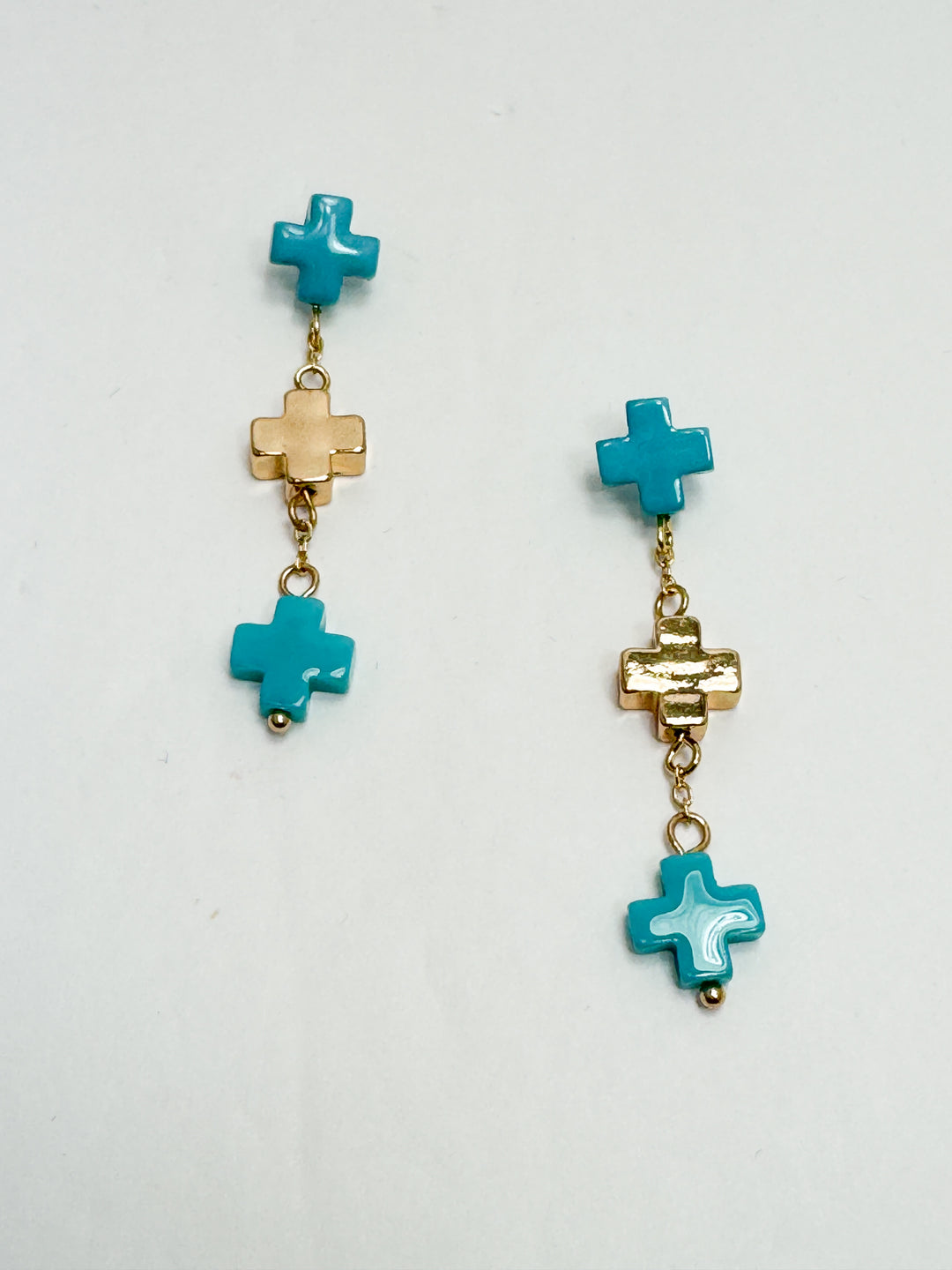 Pair of earrings with turquoise cross-shaped beads on a white background