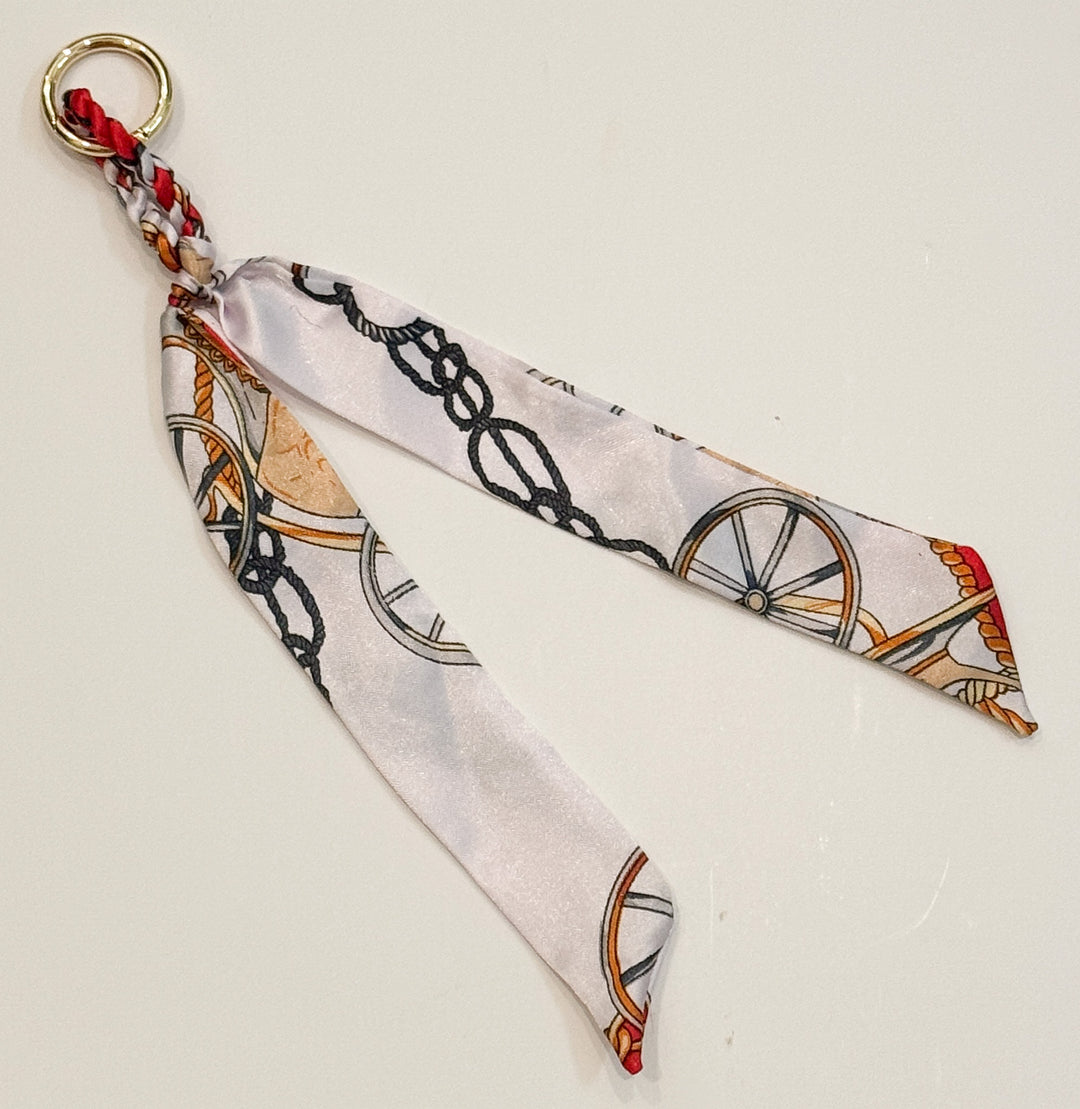 Decorative purse charm with a pattern of wheels and chains on a light background