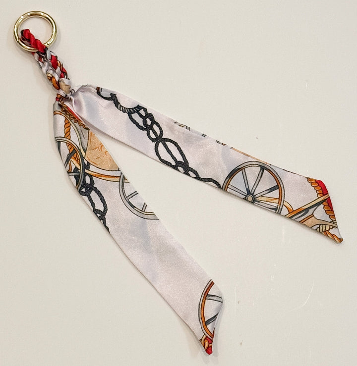 Decorative purse charm with a pattern of wheels and chains on a light background