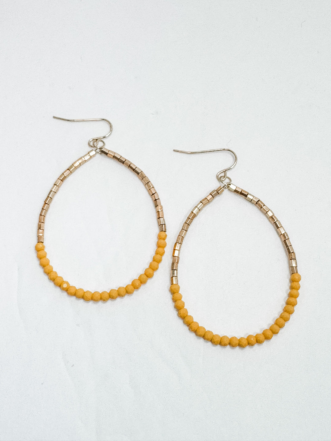 Pair of hoop earrings with yellow beads on a white background