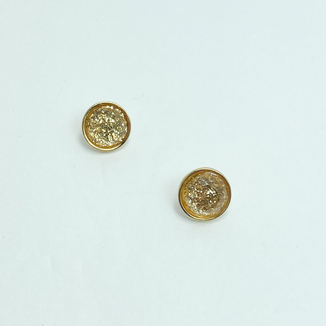 A pair of gold-colored round stud earrings with a sparkle effect on a white background